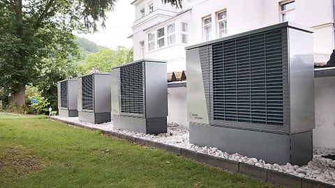 Outdoor heat pump units installed beside a modern building with landscaped surroundings