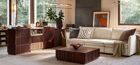 Modern living room with a white sofa, wooden furniture, large windows, and indoor plants