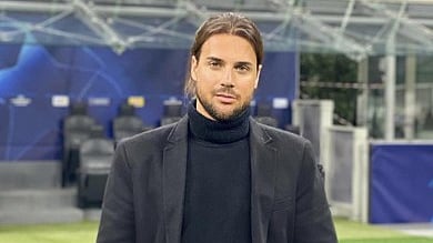 Person posing on a football field wearing a black jacket and turtleneck