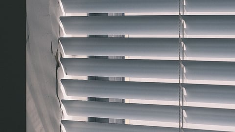 White window blinds with sunlight filtering through in a minimalist interior