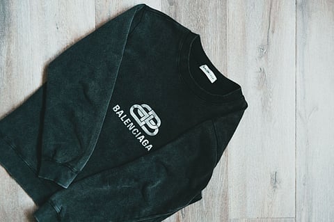 Black Balenciaga sweatshirt laid on a wooden floor.