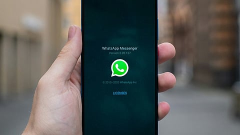 Hand holding a smartphone displaying WhatsApp Messenger.
