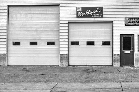 Black-and-white photo of an auto repair shop with two garage doors.
