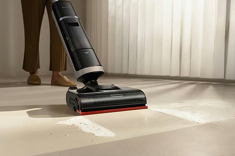 Upright wet-dry vacuum cleaning a spill on the floor.