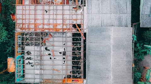 Aerial view of a damaged building surrounded by greenery.