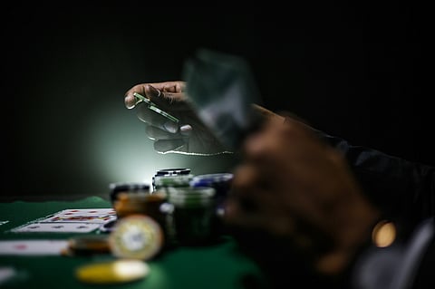 A person holds playing cards and poker chips 