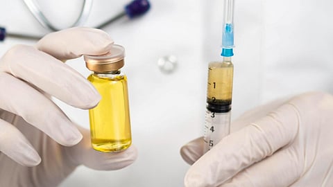  A doctor in a white coat holds a syringe and a vial