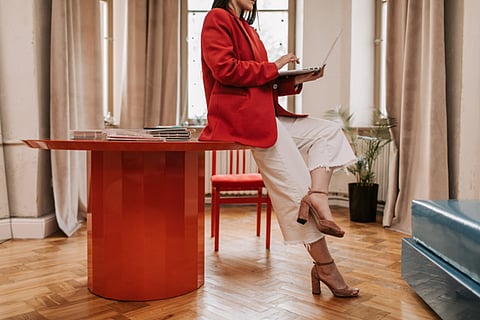 Person in a red blazer working on a laptop 