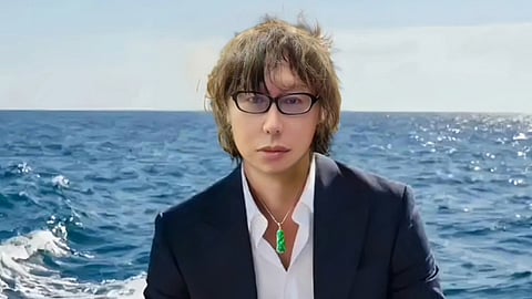 A man in a suit and glasses sits on a boat