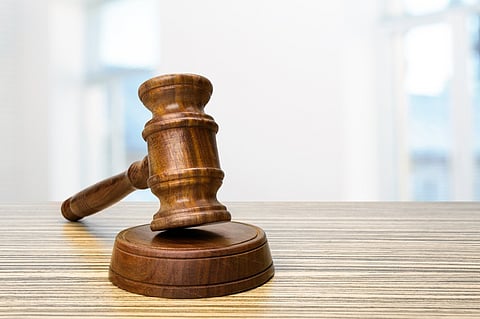 A wooden judge's gavel and sound block resting on a desk with a blurred, bright background.