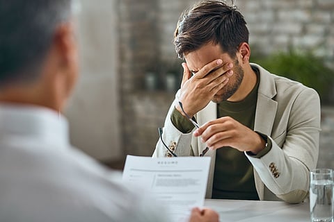 A stressed man covering his face during a job interview.