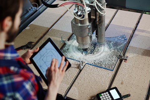 Operating CNC machine with tablet.