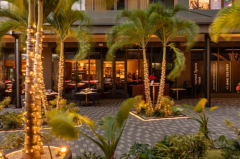 Open-air courtyard at Atlantic Village with palm trees and cafe tables
