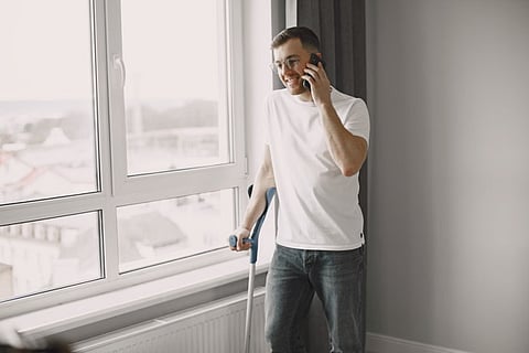 Man on phone with crutch.