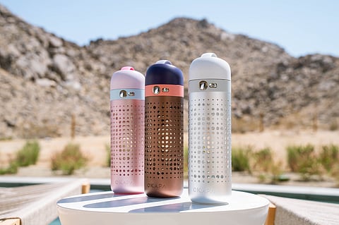 Three OKAPA designer water bottles displayed on a white round table.