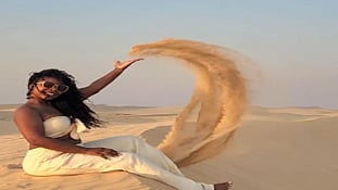 Woman throwing sand in a desert.