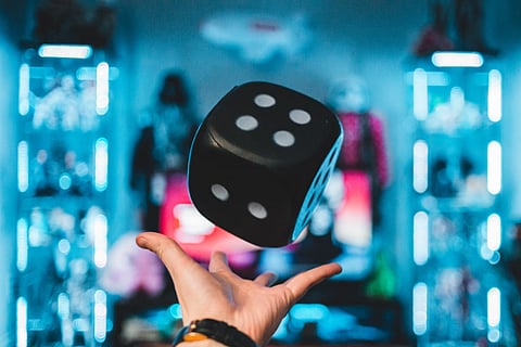 Hand tossing a large black die.