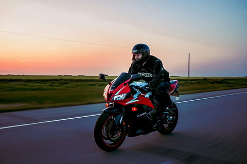 Person riding a red motorcycle at sunset.