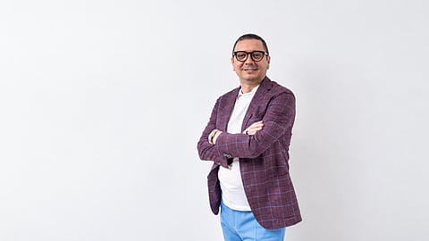 Man in a plaid blazer with arms crossed.
