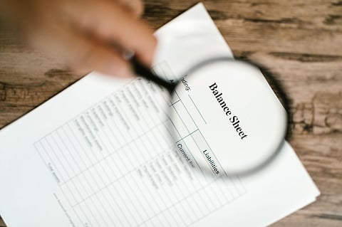 Magnifying glass over balance sheet.