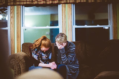 Two upset women sitting on a couch.