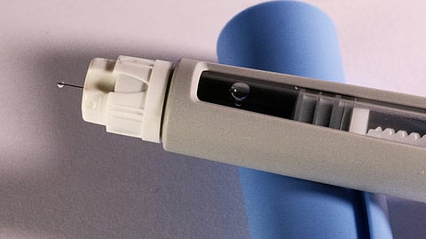 Injection pen with exposed needle.
