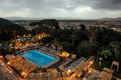 Resort pool overlooking a city at dusk.