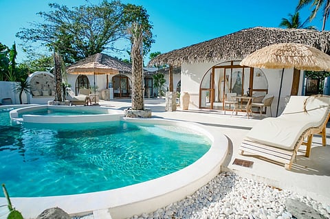 Tropical resort pool and thatched-roof villas.