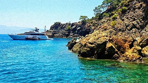 Yacht anchored near a rocky cliff.   