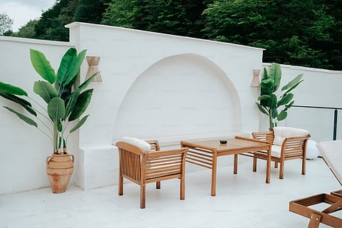 White patio with wooden furniture and potted plants