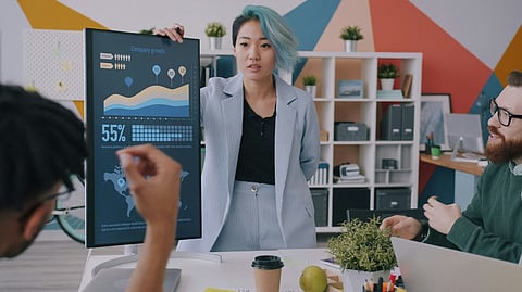 Woman presenting data charts on a screen to colleagues.