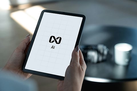 Hands holding a tablet displaying the Meta AI logo.