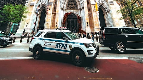NYPD car parked in front of a gothic cathedral.
