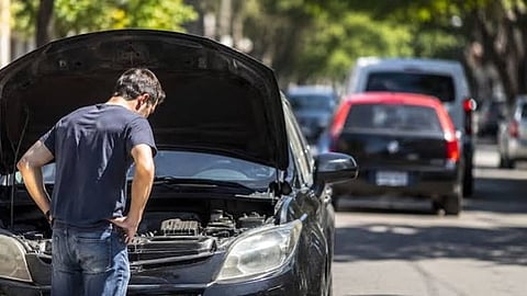 Man looking under open car hood.