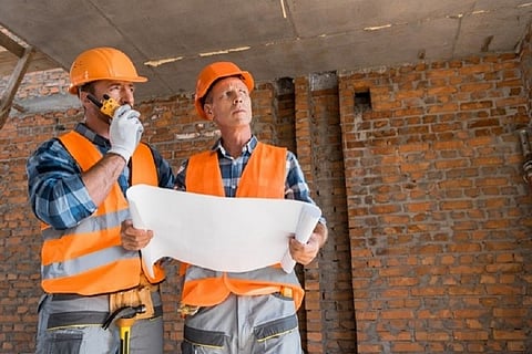 Two construction workers with blueprints.