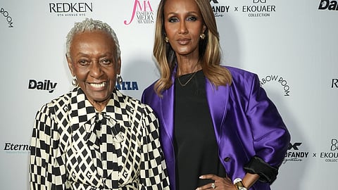 Bethann Hardison holding a crystal award beside Iman on a red carpet backdrop