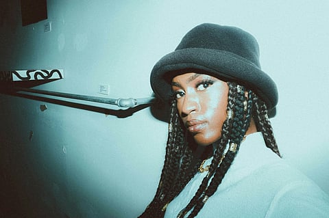 Woman with braids wearing a black bucket hat.