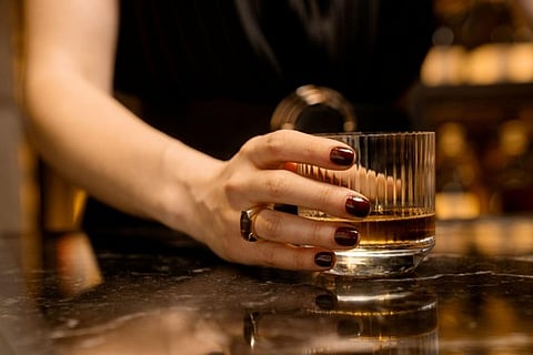 Hand holding a glass of whiskey.