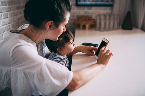 Woman and child looking at a smartphone.