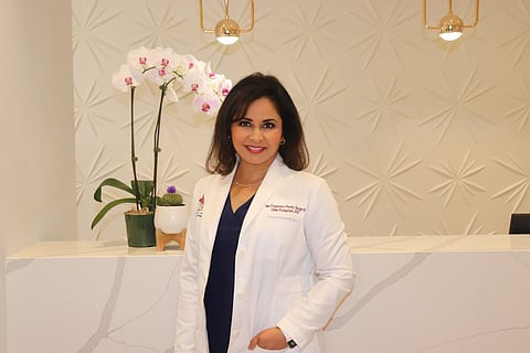 Female doctor standing at a clinic reception desk.