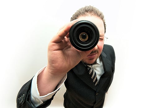 Man looking through a camera lens.