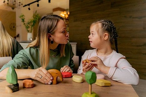 Woman and child playing with wooden toys.