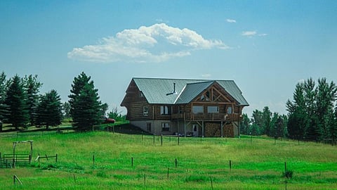 Log cabin in a green field.