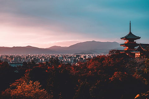 Pagoda overlooking a city at sunset.