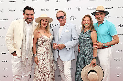 Five guests pose before the sponsor wall at the Hamptons Concours d’Elegance