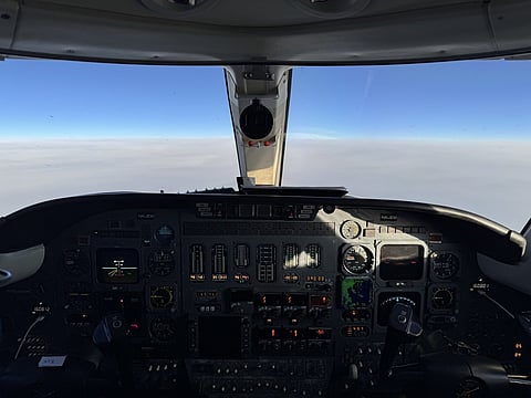 View from a private jet cockpit above the clouds, with the instrument panel in the foreground