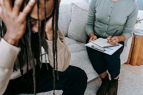 Therapist taking notes behind a distressed patient.