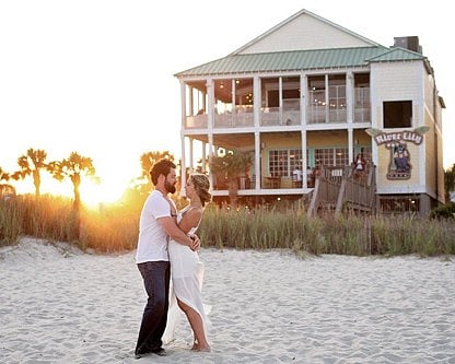 Couple embracing on a sandy beach at sunset.