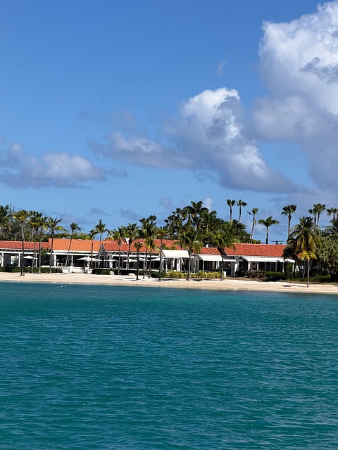 Jumby Bay Island's red-roofed resort buildings across turquoise water, Antigua