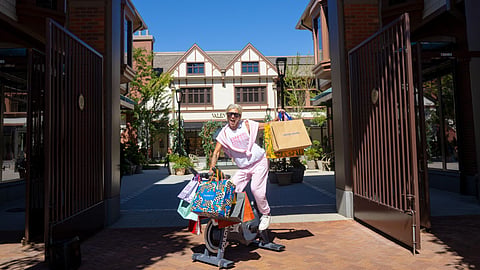 Woman seated on a stationary bike outside the Belmont Park Village entrance